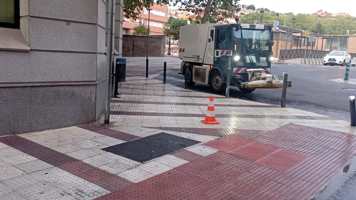 Operarios del servicio municipal realizan labores de limpieza viaria en una calle de Puertollano.
