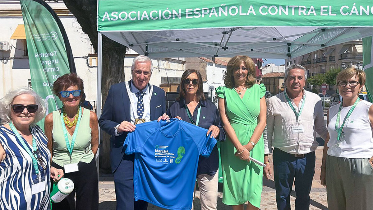 En el centro, el alcalde y la presidenta de la Junta Local, muestran la camiseta de la marcha 2026 en la cuestación del pasado domingo